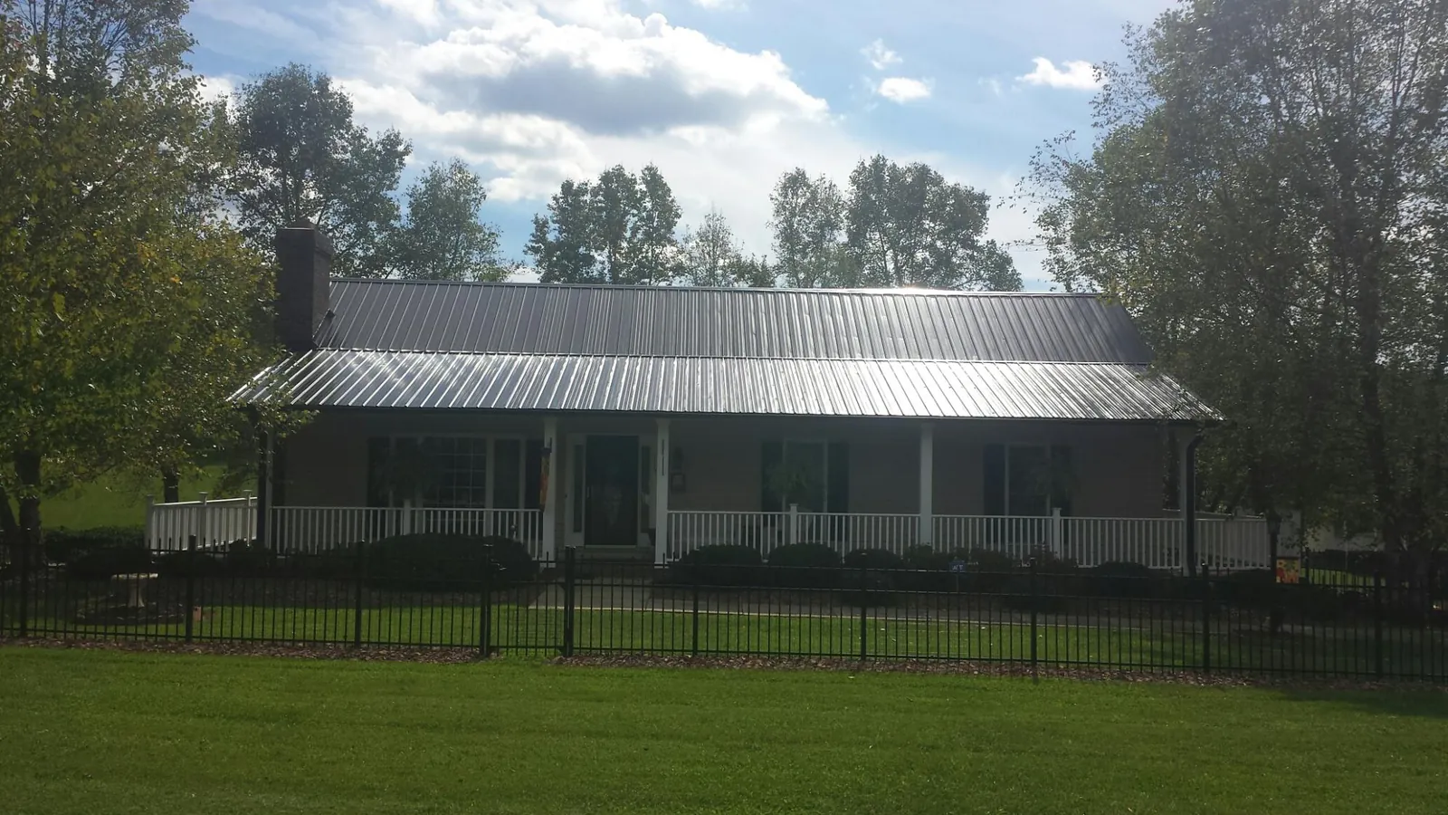 Gray metal roof on a brick ranch with a full width front porch — Gutter Guard Installation work by our crew in Elkton